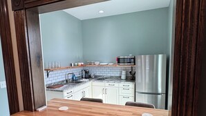 A modern kitchen with white cabinets, a stainless steel refrigerator, and a wooden dining table with four chairs. - Stadium Stay #4  The Presidents Suite.  Free Parking.  (Indianapolis)