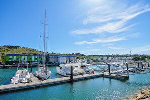 Una marina con barche ormeggiate, un edificio verde con tetto blu e un cielo azzurro limpido.