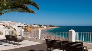 Een strandboulevard met banken, een palmboom en uitzicht op het strand en de oceaan.