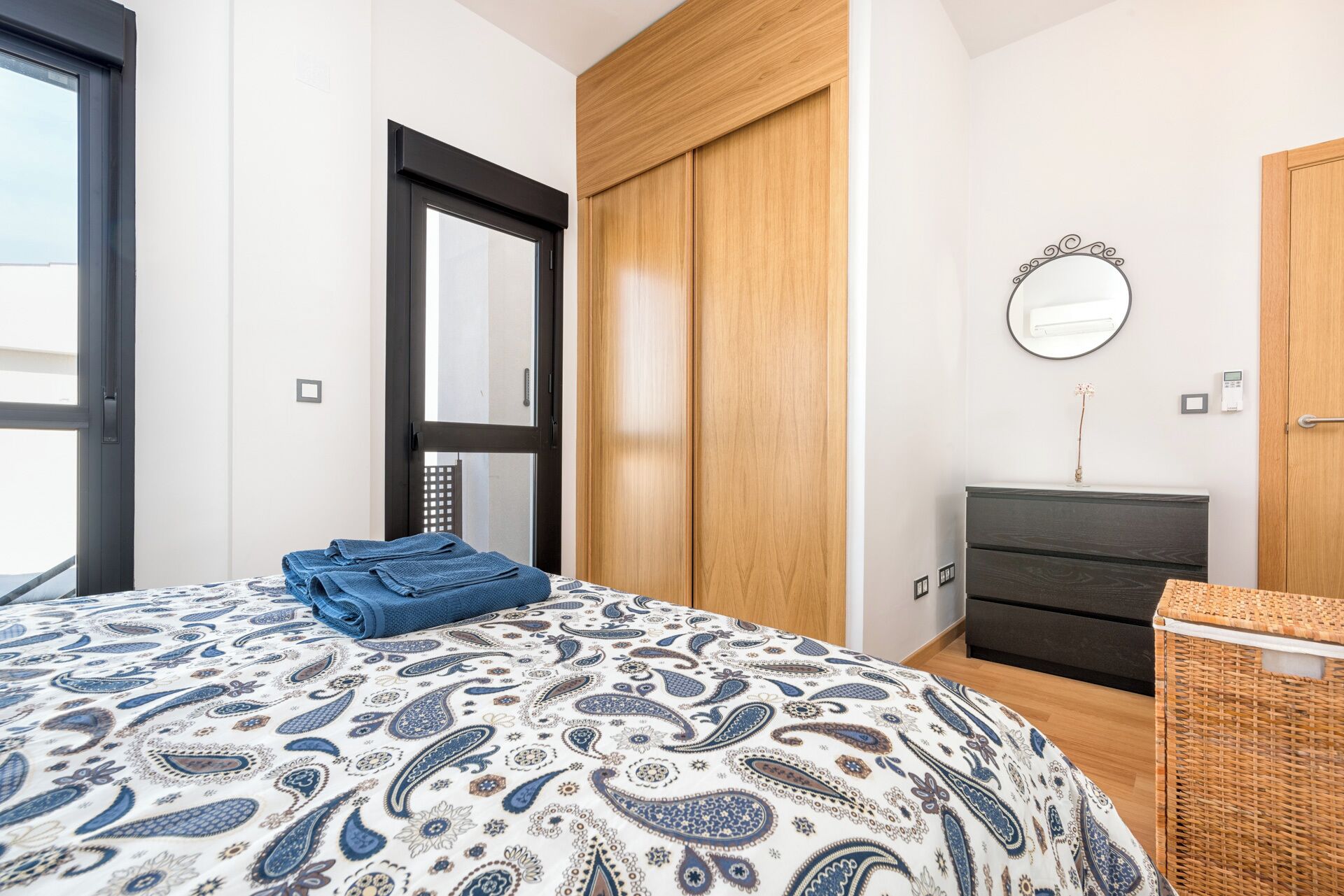 A bedroom with a bed, a wardrobe, a dresser, a mirror, and a window.