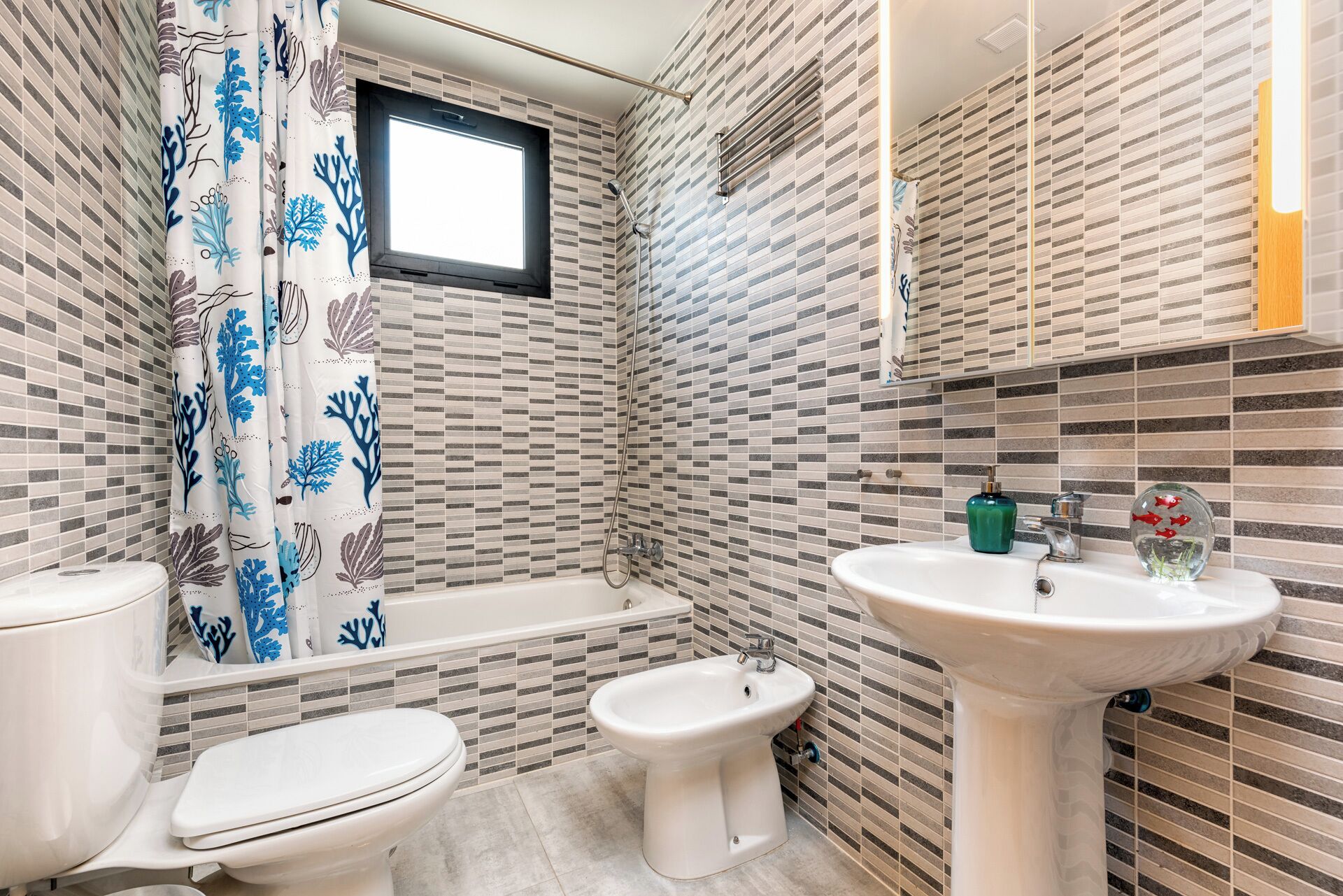 A bathroom with a toilet, bidet, bathtub, and a sink.