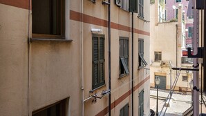 Een smalle straat met gebouwen, voorzien van traditionele luiken en een zichtbaar balkon.