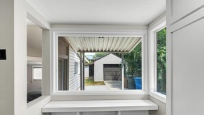 A room with a built-in bench under a large window, offering a view of a backyard with a house and greenery. - Relaxing & Stylish: Close to Downtown ~ Yard ~ Pkg (Salt Lake City)