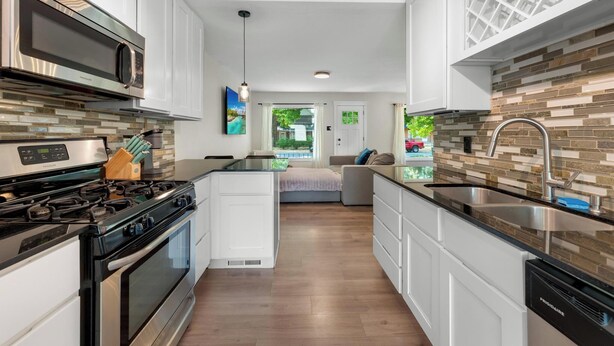 A modern kitchen with stainless steel appliances, white cabinetry, and a view to the outside. - Relaxing & Stylish: Close to Downtown ~ Yard ~ Pkg (Salt Lake City)