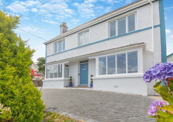 Stunning two-story residence with a charming front porch and lush green surroundings.