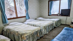 A room with three beds, a blue sofa, and a television on a stand. - pensionpure (Iiyama)