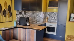 Una cocina compacta con una isla central, horno empotrado y microondas.