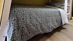 Una cama litera con un edredón estampado, una escalera de madera y un cabecero blanco.