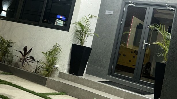 Fachada moderna de un edificio con puerta de vidrio, plantas en macetas y un vestíbulo bien iluminado.