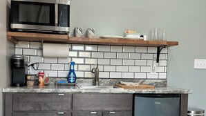 Une cuisine moderne avec des meubles de couleur bois foncé, un réfrigérateur en acier inoxydable, un four à micro-ondes et une machine à café.