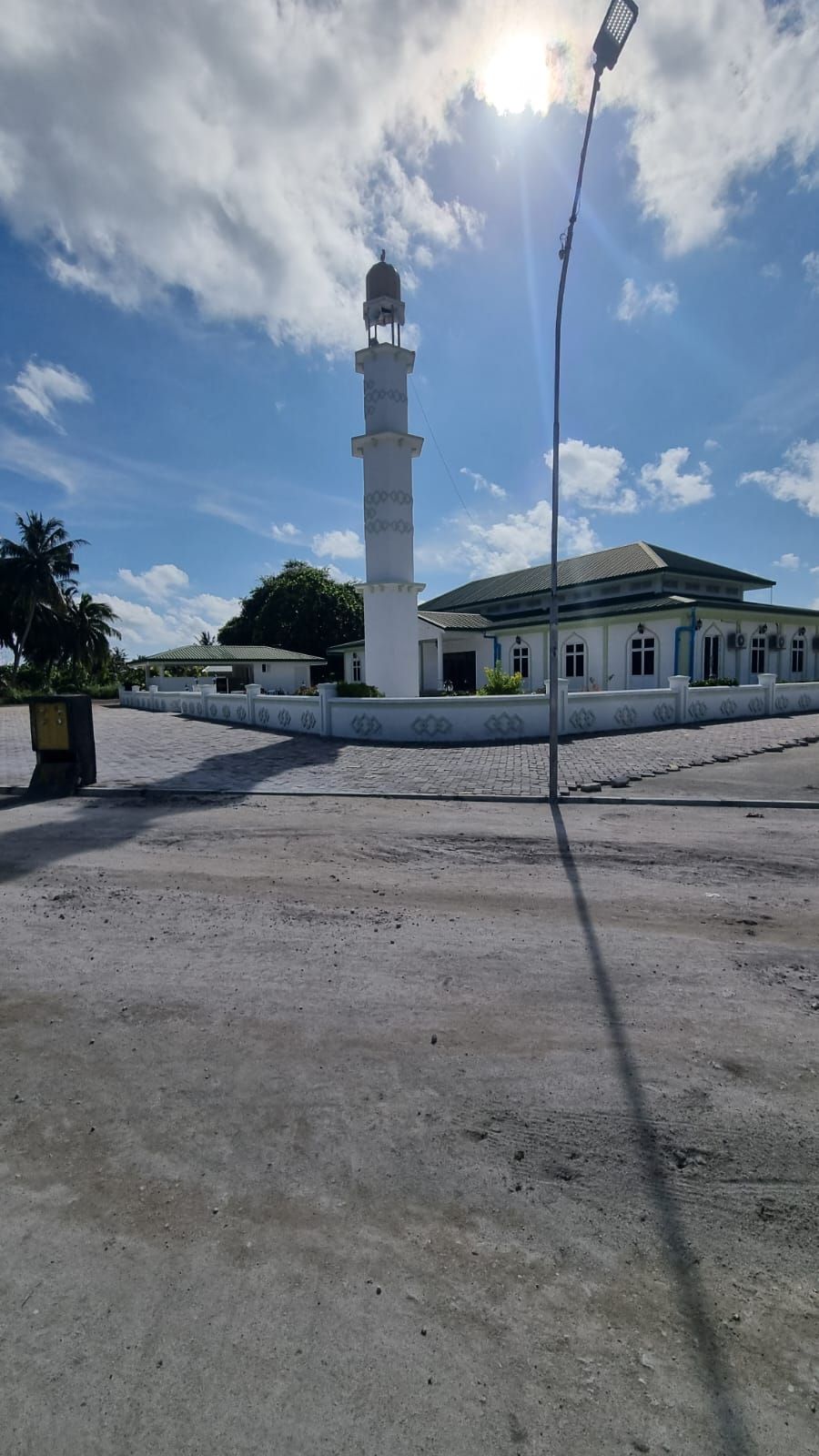 Una moschea con un minareto alto, una sala di preghiera coperta e un cortile lastricato.