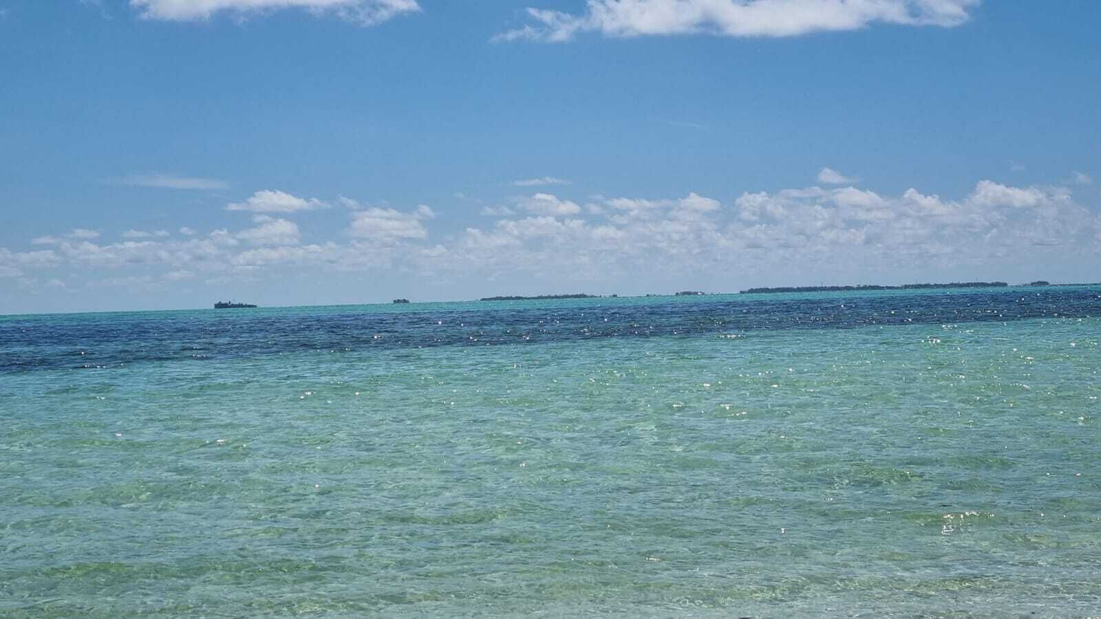 Una vista despejada del océano con una isla lejana y un barco.