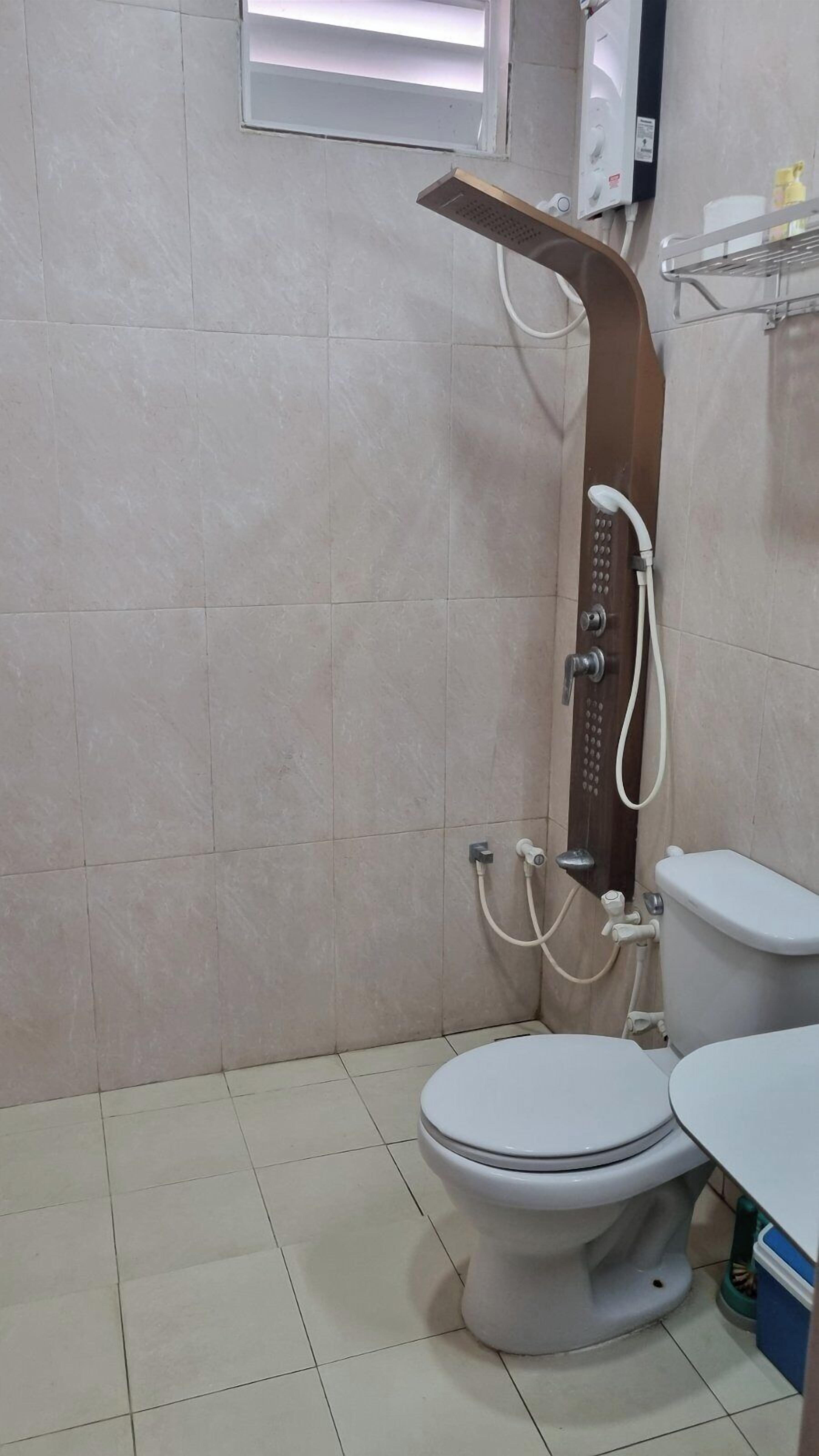 Een badkamer met douche, toilet en wastafel.