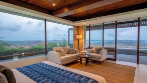 Une chambre spacieuse avec un grand lit, un canapé et une table basse. La chambre est dotée de grandes fenêtres qui offrent une vue sur le paysage.