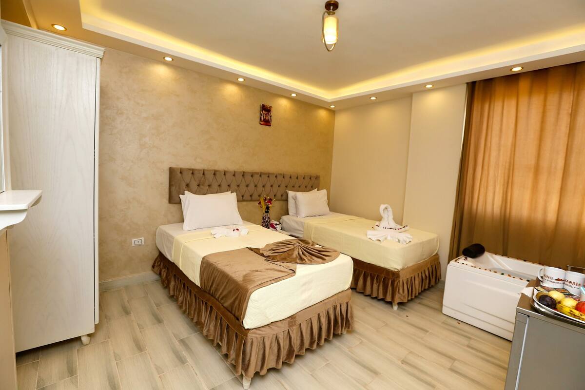 A hotel room with two beds, a vanity, and a small kitchenette.