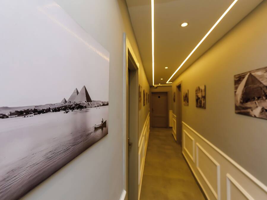 A hallway with a large black and white photograph of a coastal scene, a modern light fixture, and several framed pictures on the walls.