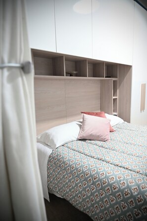 A bedroom with a bed, a headboard, and built-in storage. - Mirabilia Suites Colosseum - Luna (Roma)