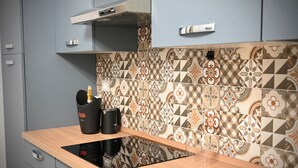 Une cuisine moderne dotée d’une plaque de cuisson à induction intégrée, de meubles gris et d’un dosseret carrelé à motifs.