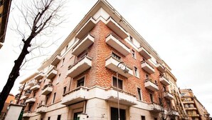 Un immeuble à plusieurs étages, doté d’une façade en briques, de balcons et d’un toit plat.