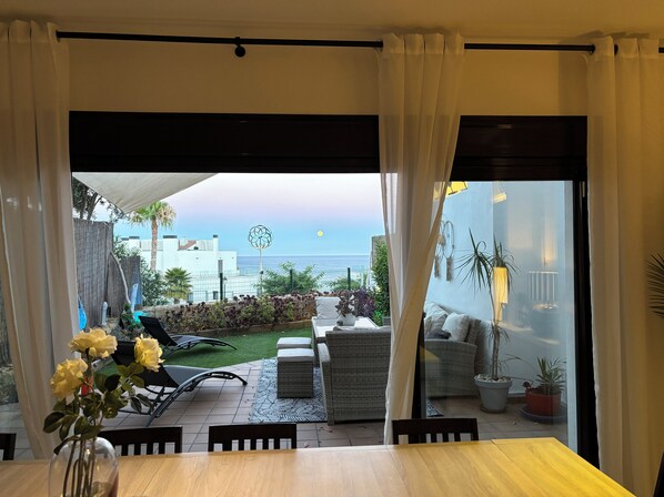 A dining area with a view of the sea, outdoor furniture, and a garden.