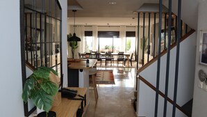 Ampla sala de estar com mesa de jantar de madeira, escada e vista para o exterior.