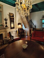 Uma sala de estar tradicional com lareira, um sofá vermelho, uma mesa de centro de madeira e um candelabro.