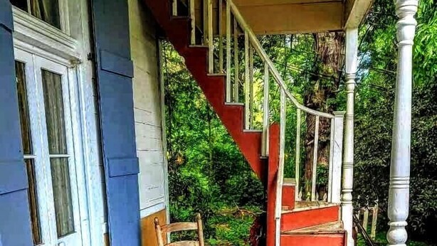 A wooden porch with a staircase leading to a covered area, surrounded by greenery. - Lafleur Guest House  (Washington)