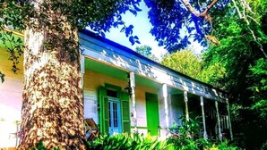 A colonial-style house with a porch, surrounded by lush greenery. - Lafleur Guest House  (Washington)