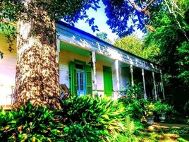 Uma casa em estilo colonial com varanda, cercada por vegetação exuberante.