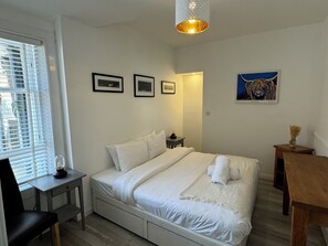 A bedroom with a bed, bedside tables, a chair, a lamp, and artwork on the walls.
