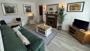A living room with a green sofa, a wooden coffee table, a fireplace, and a television. - Angel Mews - Westend Glasgow Uni Cottage (Glasgow)