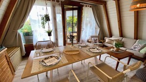 A cozy dining area with a wooden table set for four, surrounded by wicker chairs. - Renoviertes Nurdachhaus in Ostfriesischer Natur am Wasser für Familien (Südbrookmerland)
