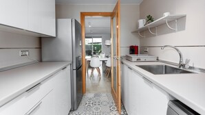 Une cuisine moderne avec des meubles blancs, un réfrigérateur en acier inoxydable, un évier et un carrelage décoratif.