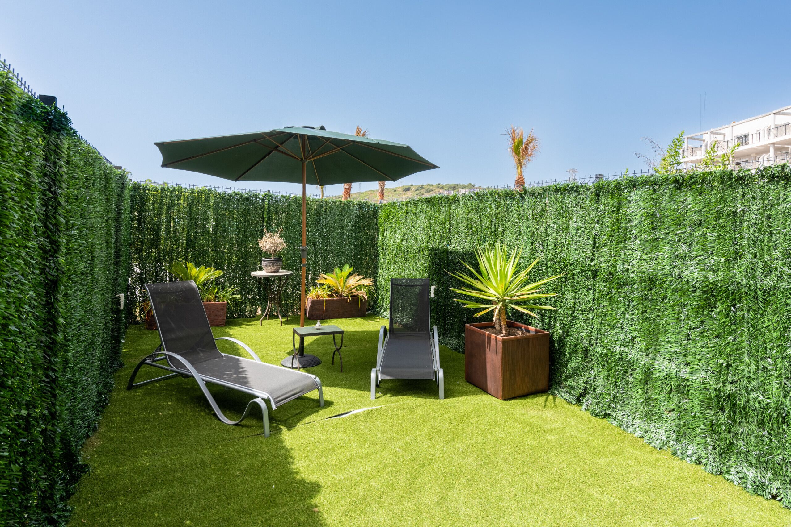 A private patio with two lounge chairs, a table, and an umbrella.