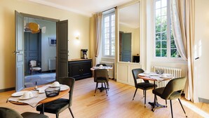 A dining area with a table set for four, a black cabinet, and a view of a garden through a window.