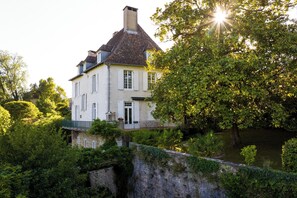 A large, white building with a steep roof, surrounded by lush greenery and a stone wall. - Villa Stella (Salies-de-Bearn)