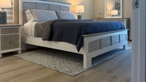 A bedroom with a bed, nightstands, a ceiling fan, and a rug. - Beachfront Sanibel Escape – Steps to Sand & Sunset Views (Sanibel)