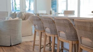 Una sala moderna con un sofá, una mesa de centro y taburetes de mimbre.