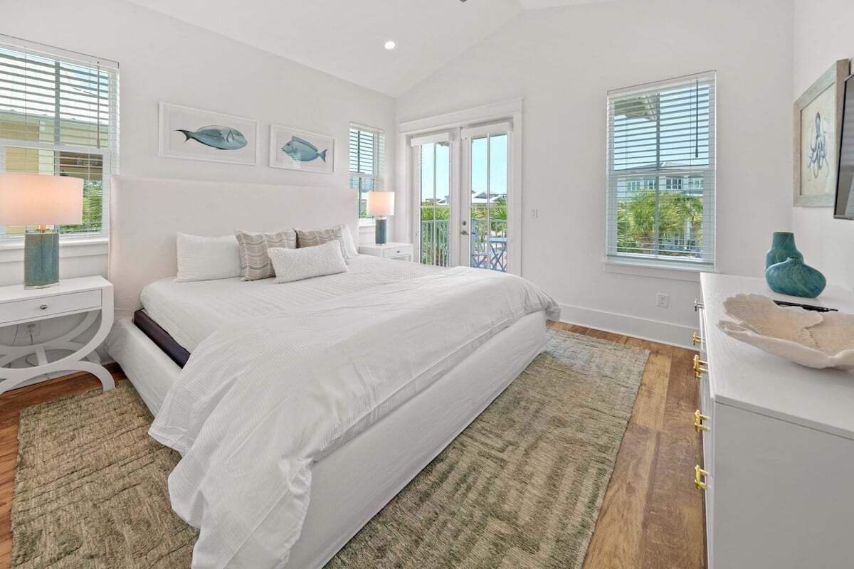 Une chambre à coucher avec un grand lit, une table de chevet, une commode et une fenêtre avec des stores.