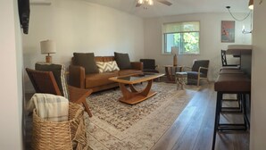 A living room with a brown leather sofa, a glass coffee table, wicker chairs, and a patterned rug. - Charming 2-bedroom condo in McHenry Close To Lake Activities and Ski Resort (McHenry)