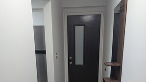 A hallway with a dark door, a wooden shelf, and a kitchen area in the background. - Charming 2-bedroom condo in McHenry Close To Lake Activities and Ski Resort (McHenry)