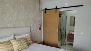 A hotel room with a bed, pillows, a nightstand, a towel rack, and a shower area. - Casa de Lazer da Chã (Alqueidão da Serra)