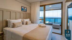 Ein Hotelzimmer mit einem großen Bett, Meerblick und einem Balkon mit einem Stuhl.