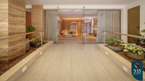Eine moderne Hotelhalle mit einer Holzwand, einer Glastür zu einem Zimmer und einer Treppe mit Geländer.