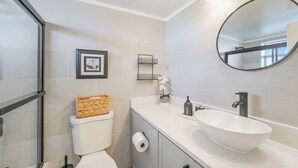 A modern bathroom with a toilet, a sink, a mirror, and a framed picture on the wall. - Stunning Studio Bay Views & Parking (North Bay Village)