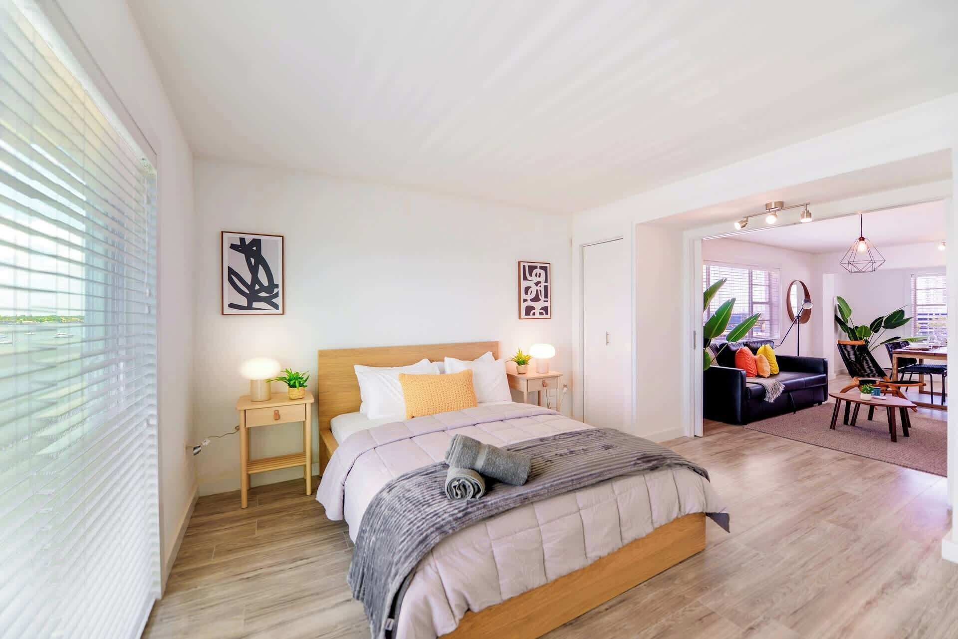 Ein modernes Schlafzimmer mit einem großen Bett, Nachttischen und Blick auf den Wohnbereich.