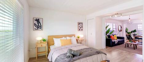 A modern bedroom with a large bed, bedside tables, and a view of the living area.
