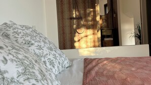 A bedroom with a bed, a mirror, and a shower area.