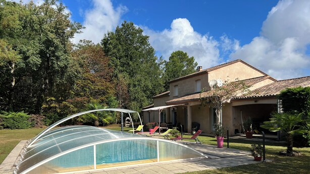 Une maison avec une piscine, un patio couvert et un jardin.