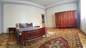 A bedroom with a wooden bed, a nightstand, a wardrobe, and a patterned rug. - Airport to Echmiadzin Guest House (Parakar)